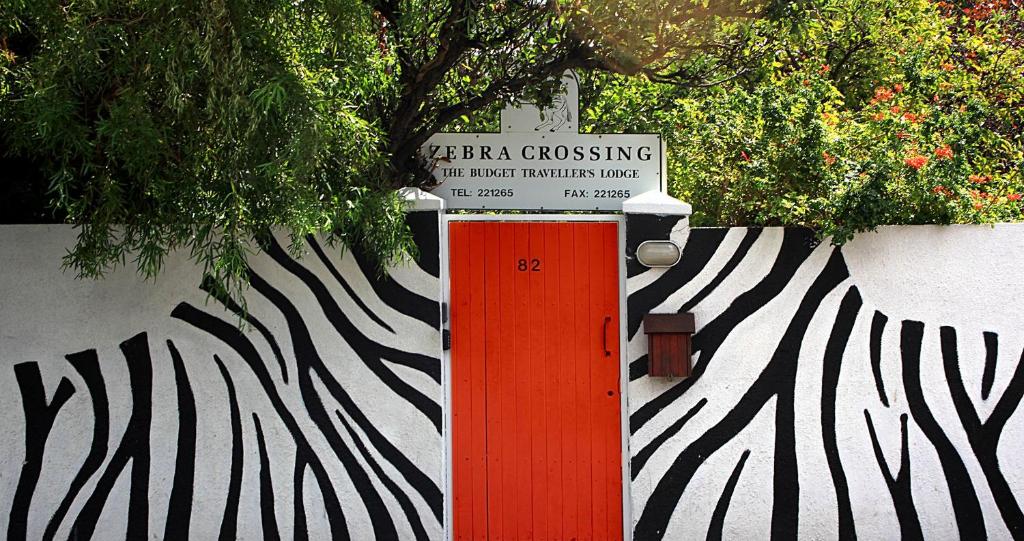 een bord op een muur met een rode deur bij Zebra Crossing Backpacker in Kaapstad
