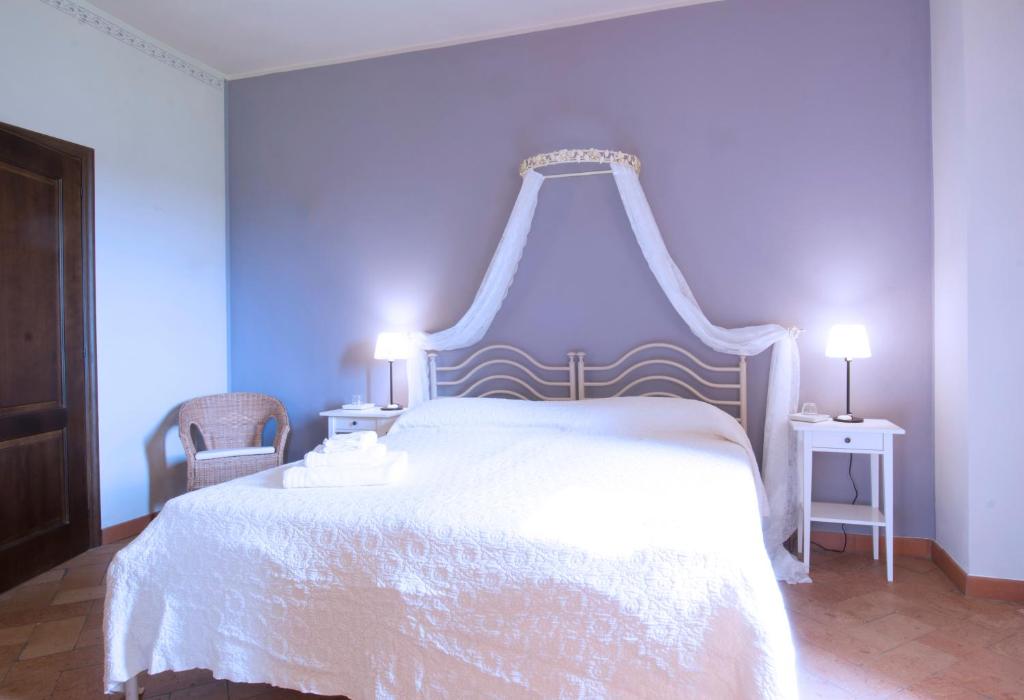 モンカルヴォにあるAgriturismo Cascina Olivettaのベッドルーム1室(白いベッド1台、椅子2脚付)