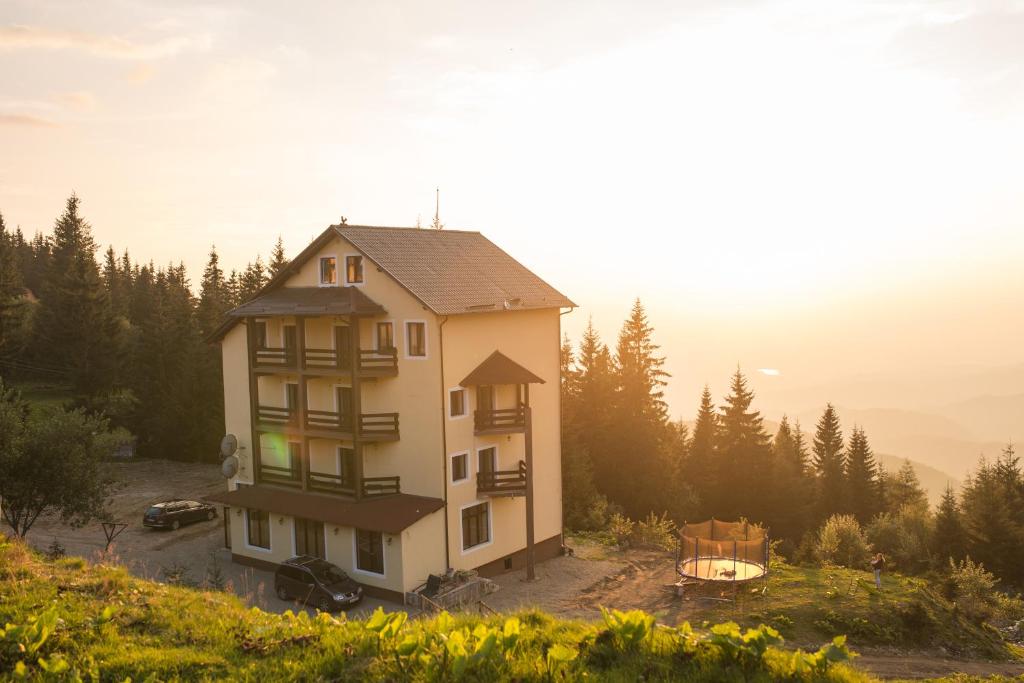 uma casa no topo de uma colina com uma lareira em Hotel Muntele Mic em Borlova