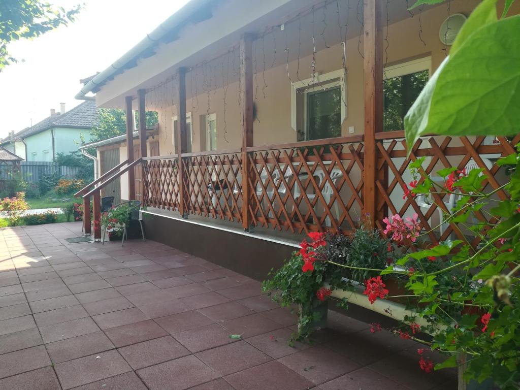 una casa con una valla y flores en un patio en Tiszavirág Apartmanház, en Szeged