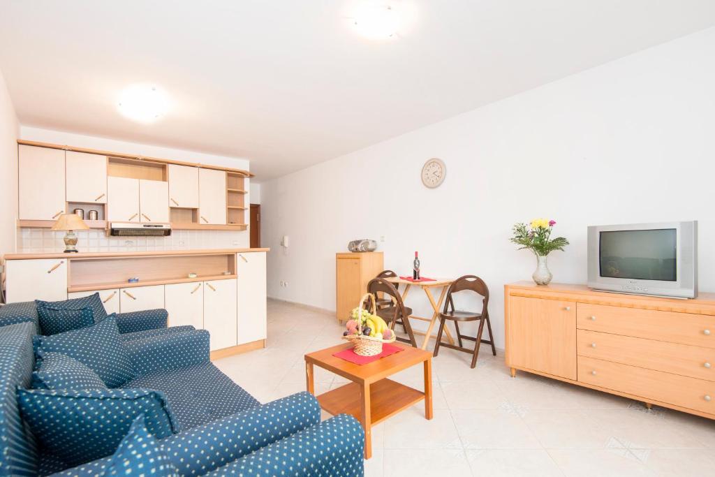 een woonkamer met een blauwe bank en een keuken bij Apartman Budva in Budva