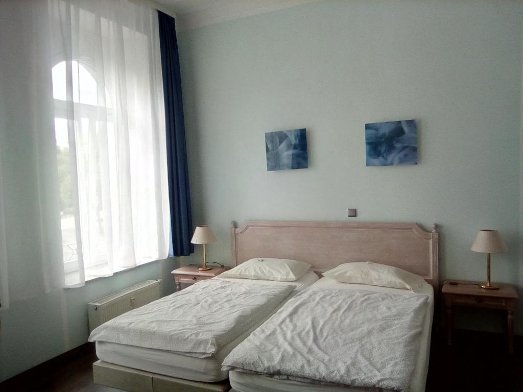 ein Schlafzimmer mit einem Bett mit zwei Lampen und einem Fenster in der Unterkunft Apartments in der Jahnallee 20 Waldplatzpalais in Leipzig
