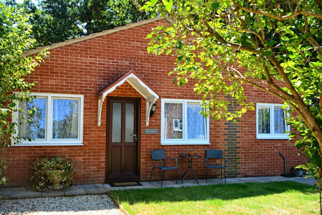 a red brick house with chairs and a door at Little Lulworth in Bordon