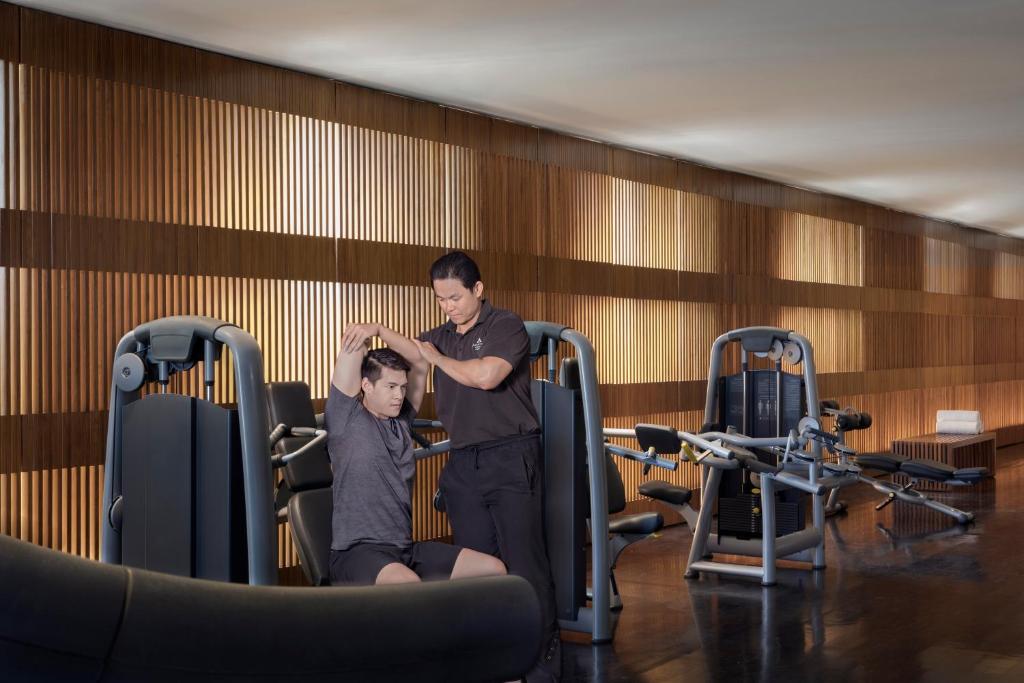 a man standing next to a man sitting in a gym at Anantara Chiang Mai Resort in Chiang Mai