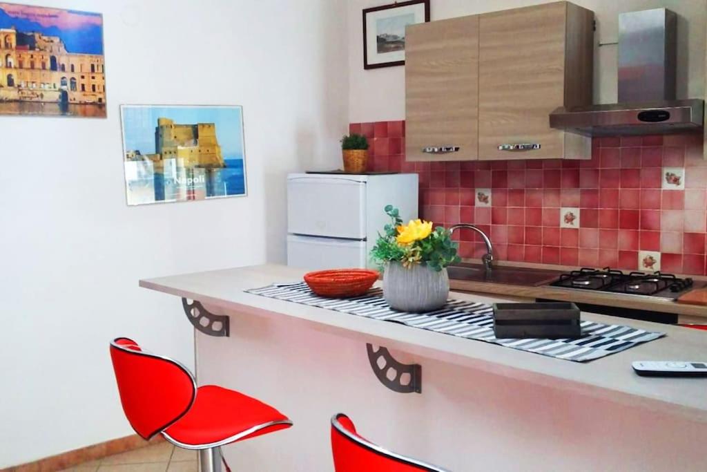 une cuisine avec des chaises rouges et un comptoir dans l'établissement Casa Vacanza le Moko', à Naples