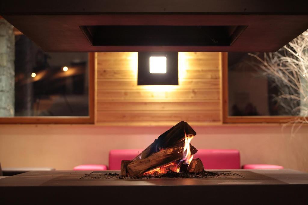 a fireplace in a table with pink chairs and a light at Résidence Le Chalet du Mont Vallon in Les Menuires