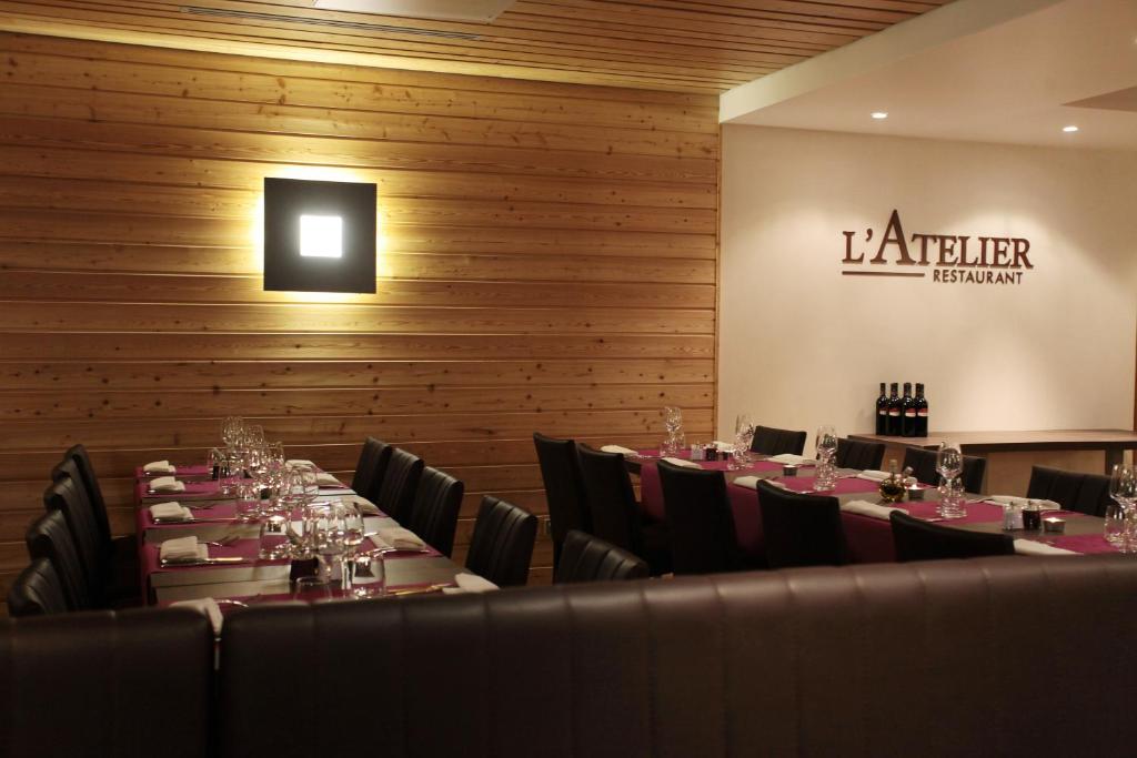 a dining room with tables and chairs and a sign on the wall at Résidence Le Chalet du Mont Vallon in Les Menuires