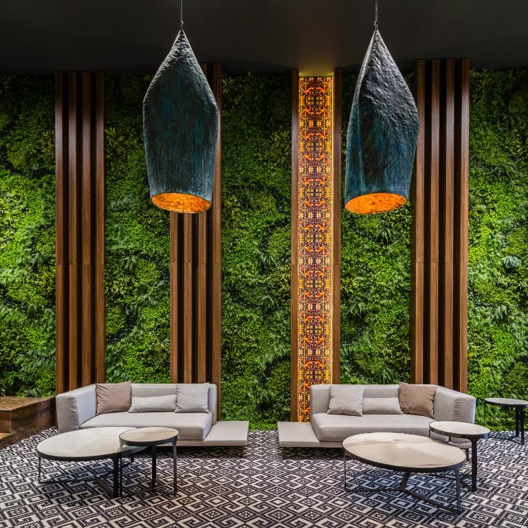 a lobby with two couches and tables in front of a green wall at Unirea Hotel & Spa in Iaşi