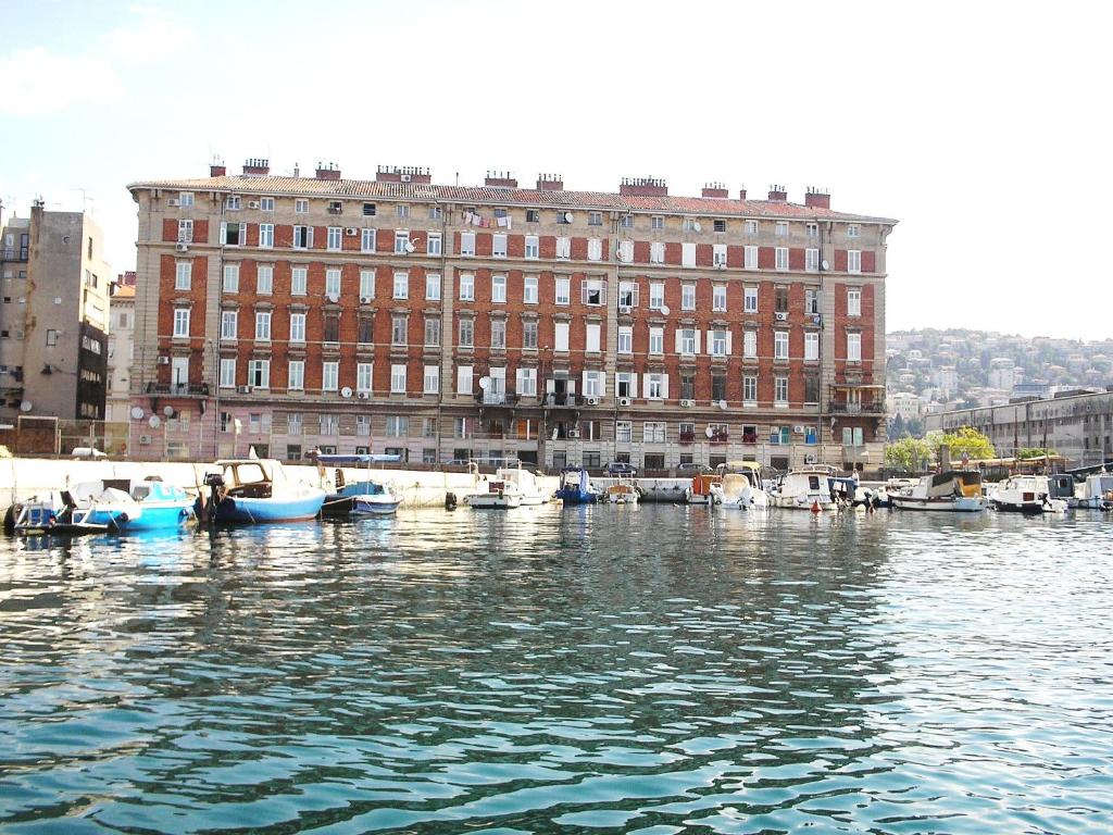 a large brick building with boats in the water at Rooms Center Demetrova in Rijeka