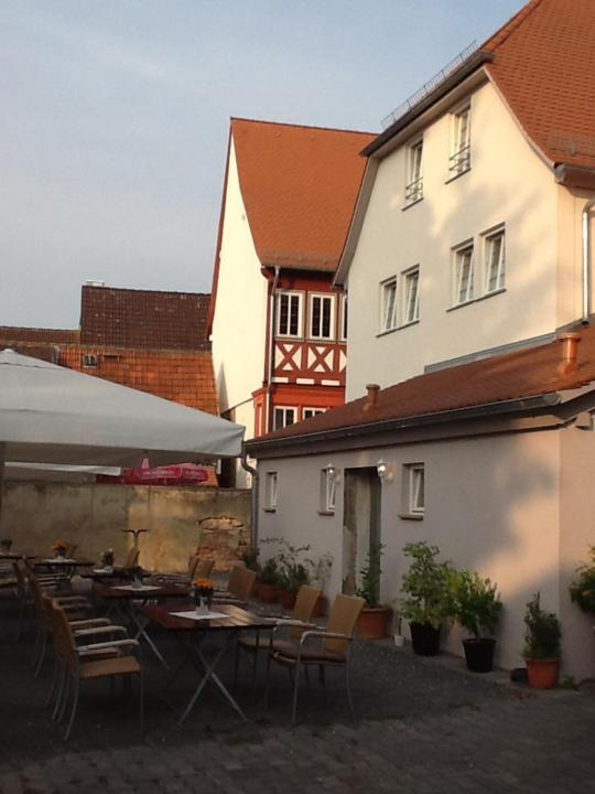 un patio avec des tables et des chaises en face d'un bâtiment dans l'établissement Hotel Adler, à Babenhausen