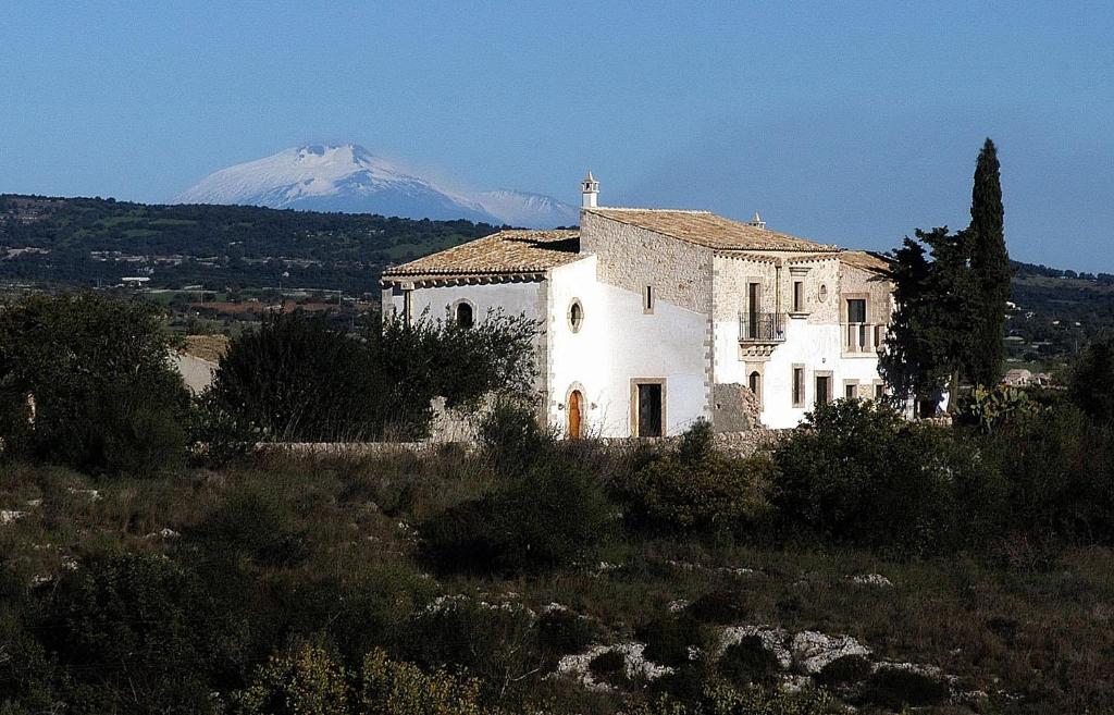 a building in a field with a mountain in the background at Casa delle Meridiane in Canicattini Bagni