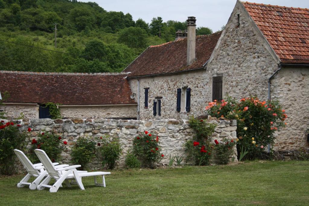 two white lounge chairs in front of a stone building at Chez Fred et Cécile in Verdilly