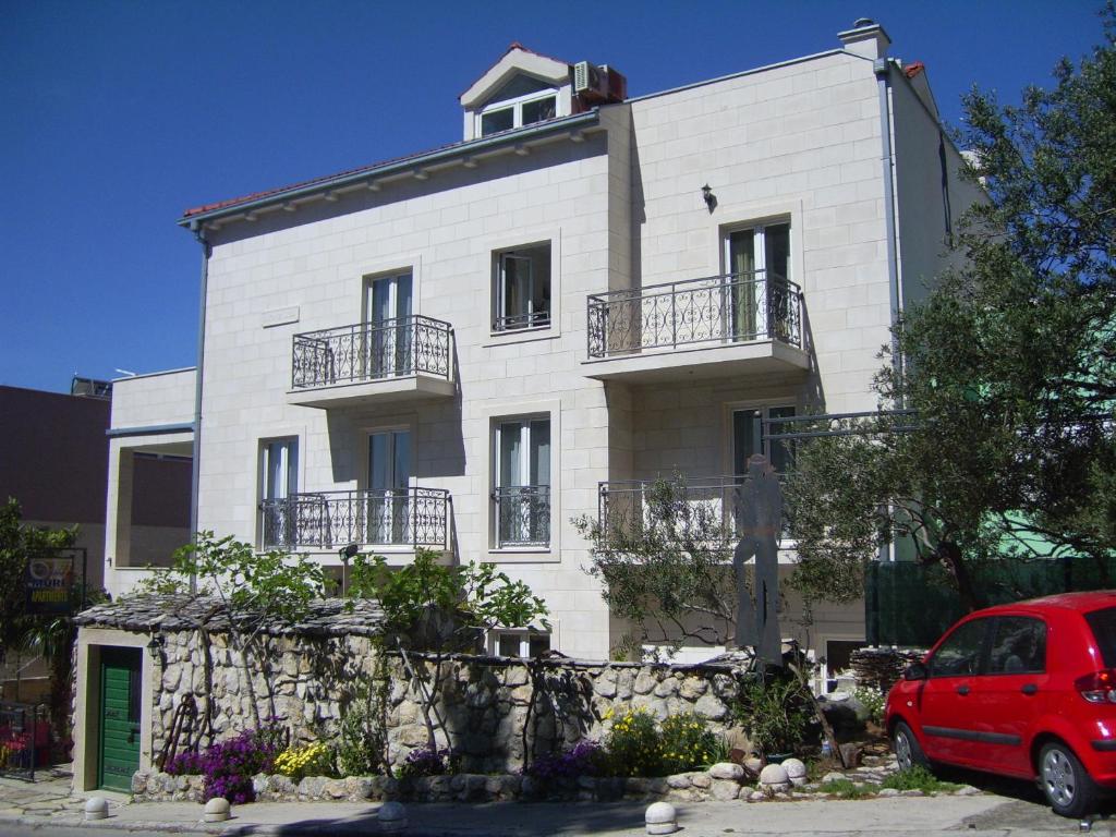 a white building with a red car parked in front of it at Apartments Villa More in Makarska