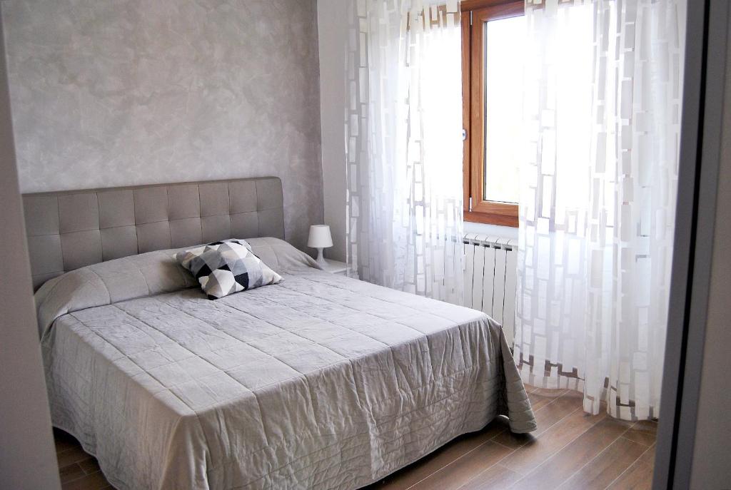 RomAmourHouse في روما: غرفة نوم بسرير مع ستائر بيضاء ونافذة