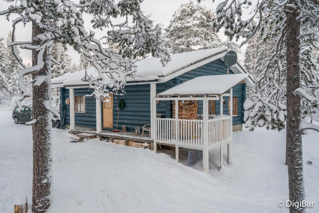 una casa azul con techo cubierto de nieve en la nieve en Auroracabin Chalets en Saariselka