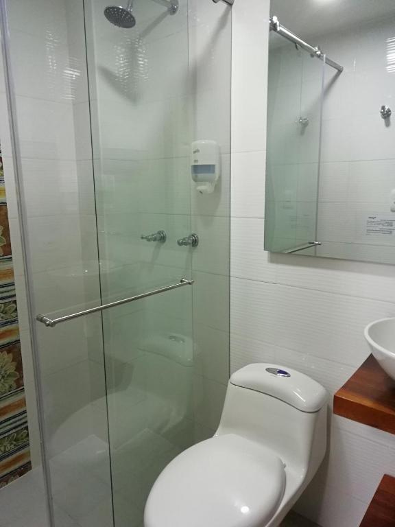 a bathroom with a toilet and a glass shower at Elizabetha Hostal in Salento