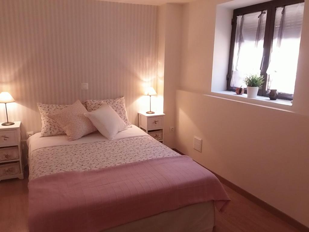 a bedroom with a bed with two night stands and two windows at Casa Rural Los Robles in Valverde de los Arroyos