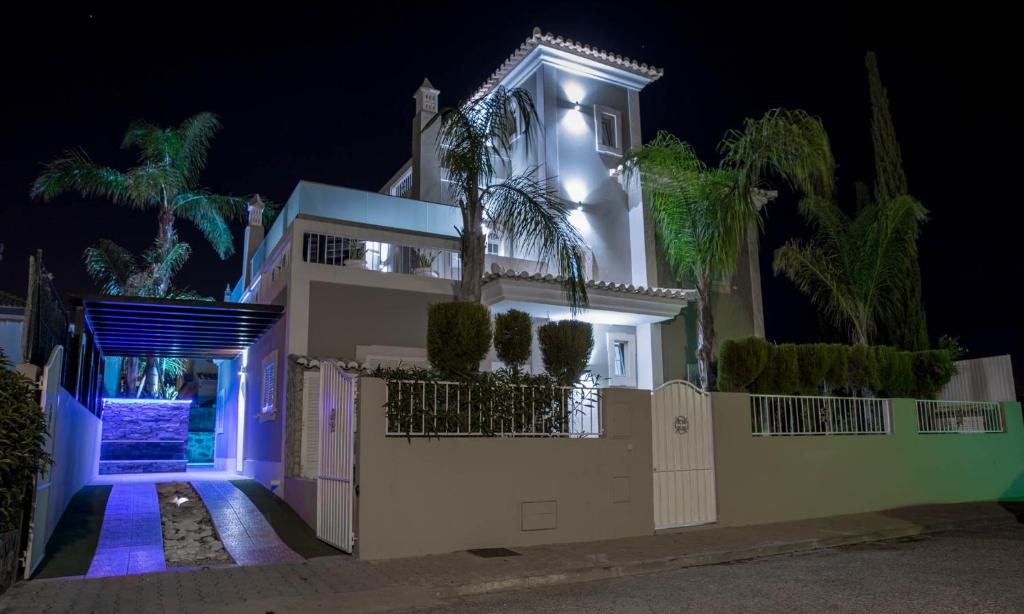a white house with blue lights in the night at Moradia Correia in Olhão