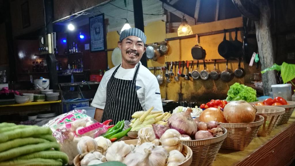 a man is standing behind a counter with vegetables at PP Red Tuna Hut in Phi Phi Don