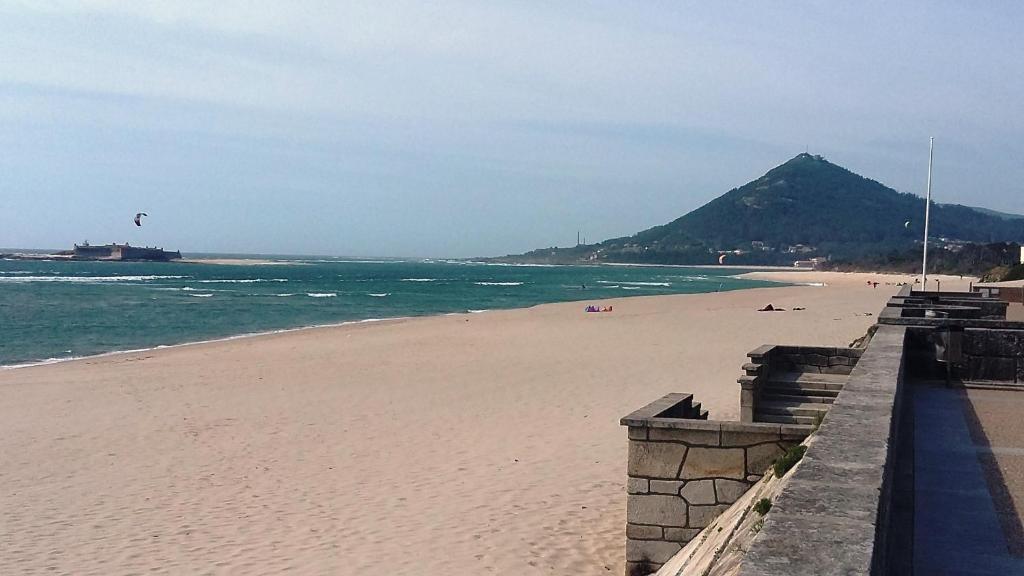 uma praia arenosa com uma montanha ao fundo em Moledo Beach - Guest Apartment em Moledo