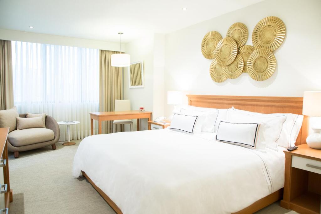 Una habitación de hotel con una gran cama blanca y una silla. en Hotel Melia Lima, en Lima