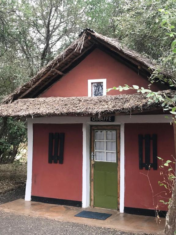 a red and white building with a green door at Maasai Simba Camp in Amboseli