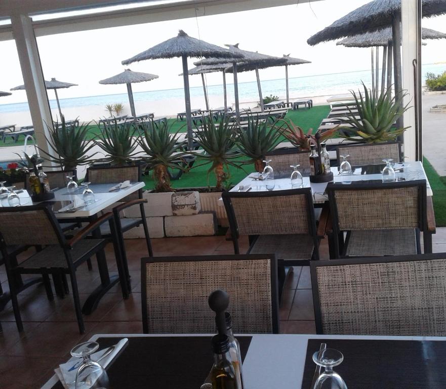 a restaurant with tables and chairs with a view of the beach at Hotel Roca Bella in Es Pujols