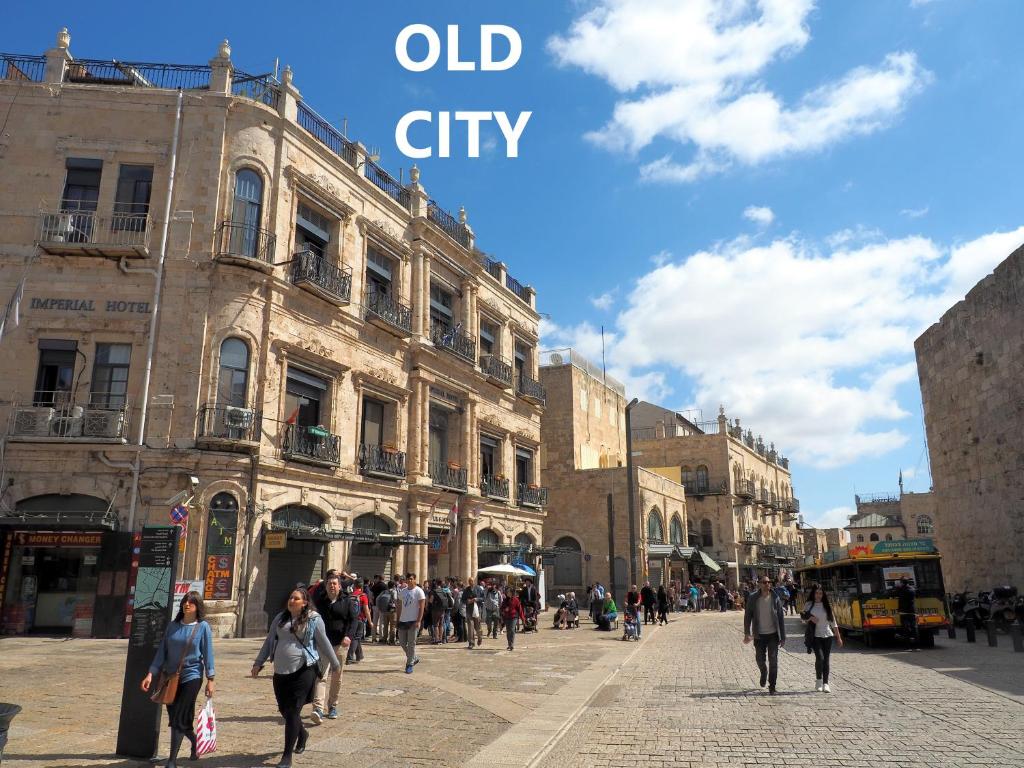 um grupo de pessoas andando por uma rua em uma cidade velha em New Imperial Hotel em Jerusalém