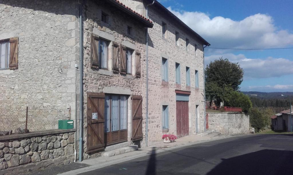 a stone building with wooden doors on a street at aux genets de josephine in Fournols