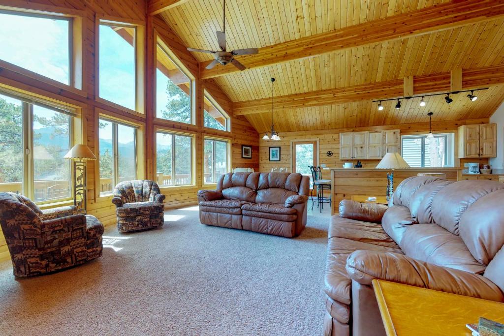 a large living room with leather furniture and windows at Twin Pines Cabin in Estes Park
