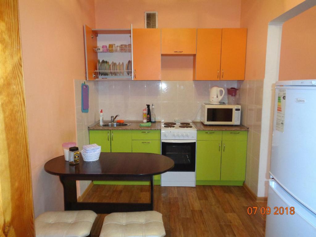 トムスクにある2-комнатная в Центре Томскаの小さなキッチン(緑のキャビネット、テーブル付)