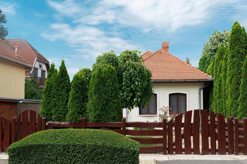 a fence in front of a house with trees at Hajdu Apartman 2. in Hajdúszoboszló