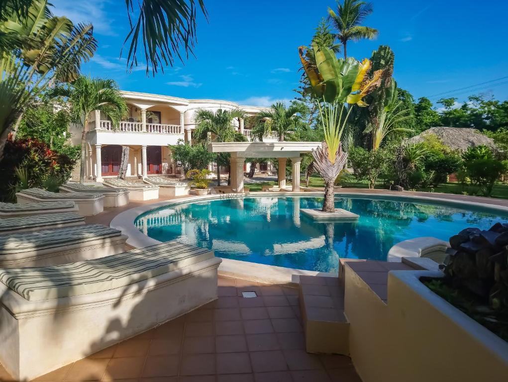 a swimming pool in front of a house with palm trees at Villa La Plantacion in Las Galeras