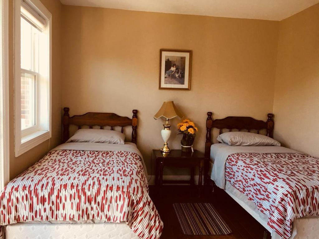 a bedroom with two beds and a table with a lamp at Seaview White House in Stratford