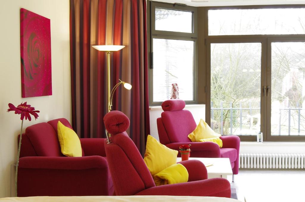 a living room with red chairs and yellow pillows at Haus Roseneck mit THERMEplus in Bad Bevensen