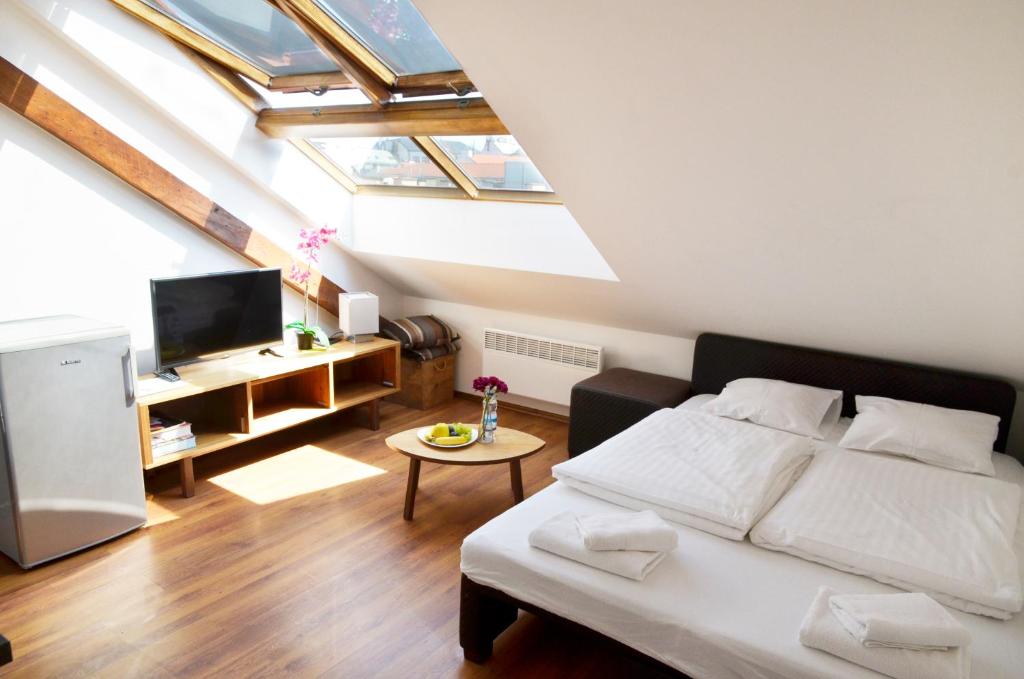 sypialnia z łóżkiem i telewizorem na poddaszu w obiekcie The Republic Apartments w Pradze