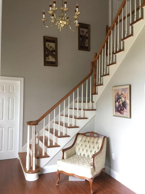 a staircase with a chair and a chandelier at Seaview White House in Stratford