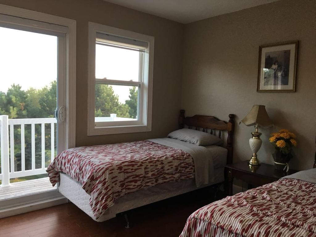 a bedroom with two beds and two windows at Seaview White House in Stratford