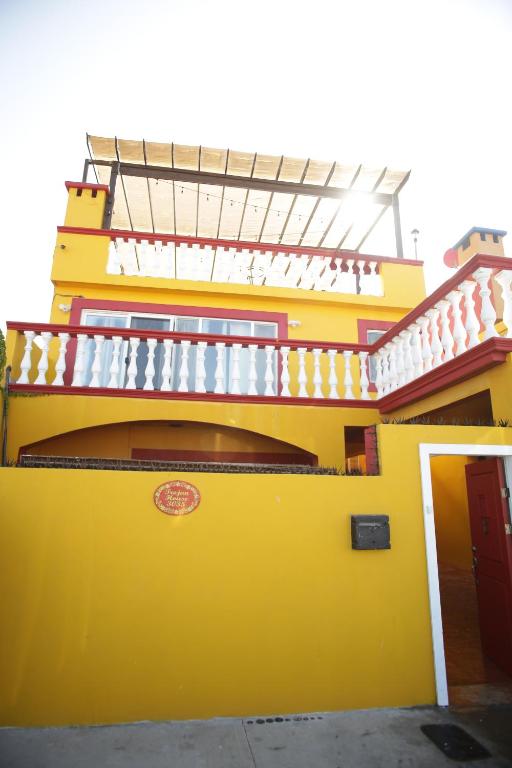 a yellow building with a balcony on top of it at Trojan House in Ensenada