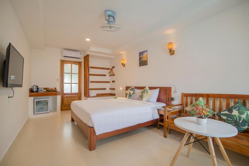 een slaapkamer met een bed en een tafel en een televisie bij Palma Resort in Phu Quoc