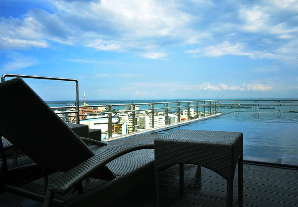 a balcony with chairs and a table and the ocean at One Central Hotel & Suites - Multiple Use Hotel in Cebu City