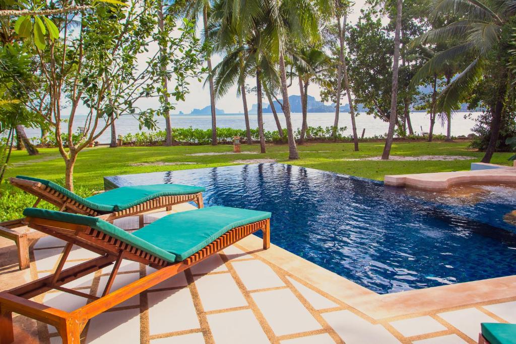 a swimming pool with two lounge chairs next to it at Amatapura Beachfront Villa 12, SHA Certified in Ao Nam Mao