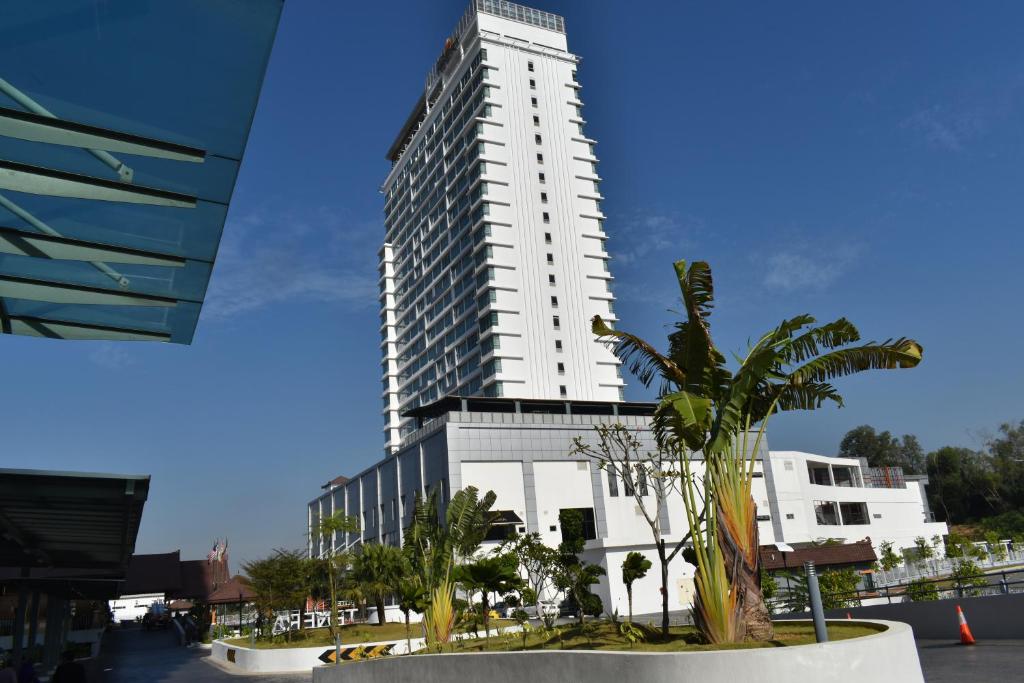 a tall white building with palm trees in front of it at Tenera Hotel in Bangi