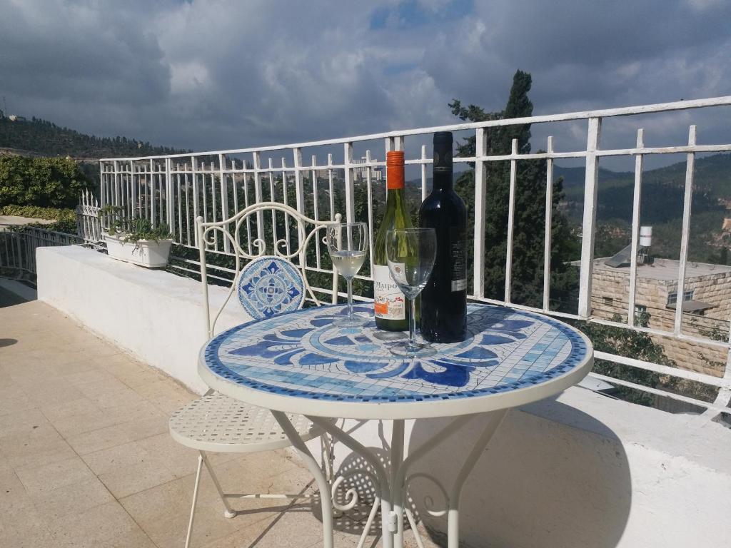 uma mesa com duas garrafas de vinho numa varanda em Avrahami Lake View em Jerusalém