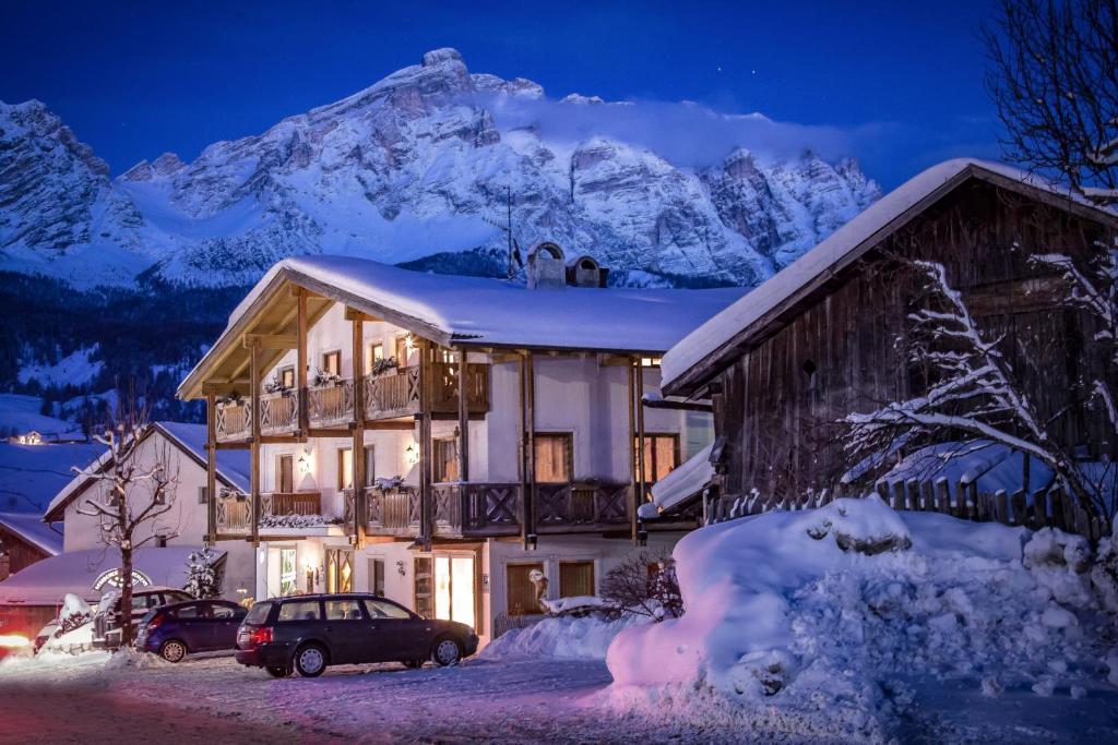 Una casa en la nieve por la noche con una montaña en Residence Sas Vanna, en La Villa