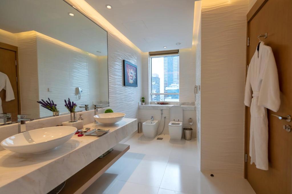 Canal Central Hotel Business Bay في دبي: حمام مع مغسلتين ودورتين مياه