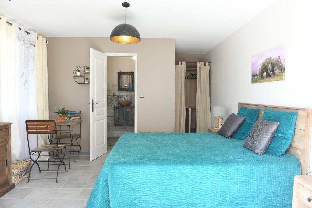 - une chambre avec un lit bleu et une salle à manger dans l'établissement Chambre d'hôtes du Charme Provençal, à Sénas
