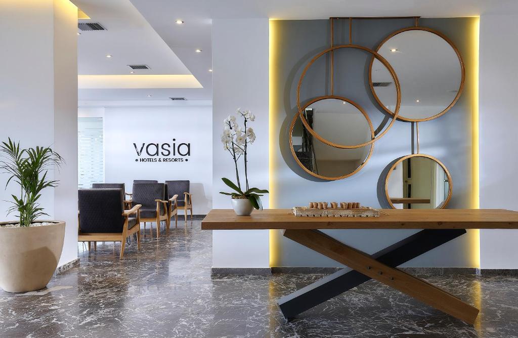 un vestíbulo con una mesa y espejos en la pared en Vasia Royal Hotel, en Gouves