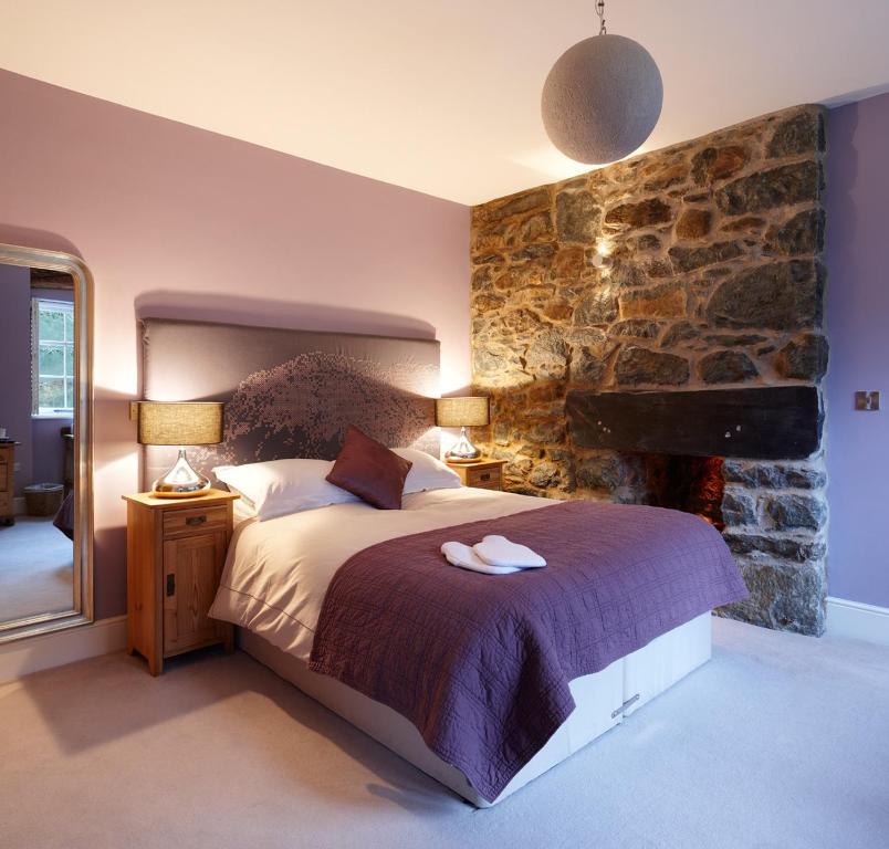 a bedroom with a bed and a stone wall at Cross Foxes - Bar Grill Rooms in Dolgellau