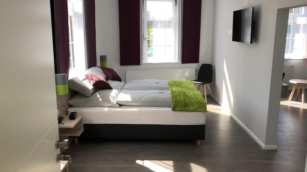 a bed sitting in a room with two windows at Landhotel Zur Bretzel in Babenhausen